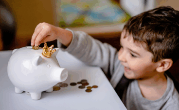 edukacja finansowa dziecka dziecko odkładające monety do skarbonki