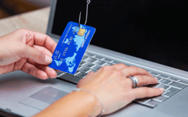 phishing ręka z kartą kredytową na haczyku przy komputerze
